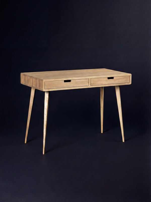 Empty HEIM 105 desk in solid oak, three-quarter view with wooden drawer fronts and splayed legs
