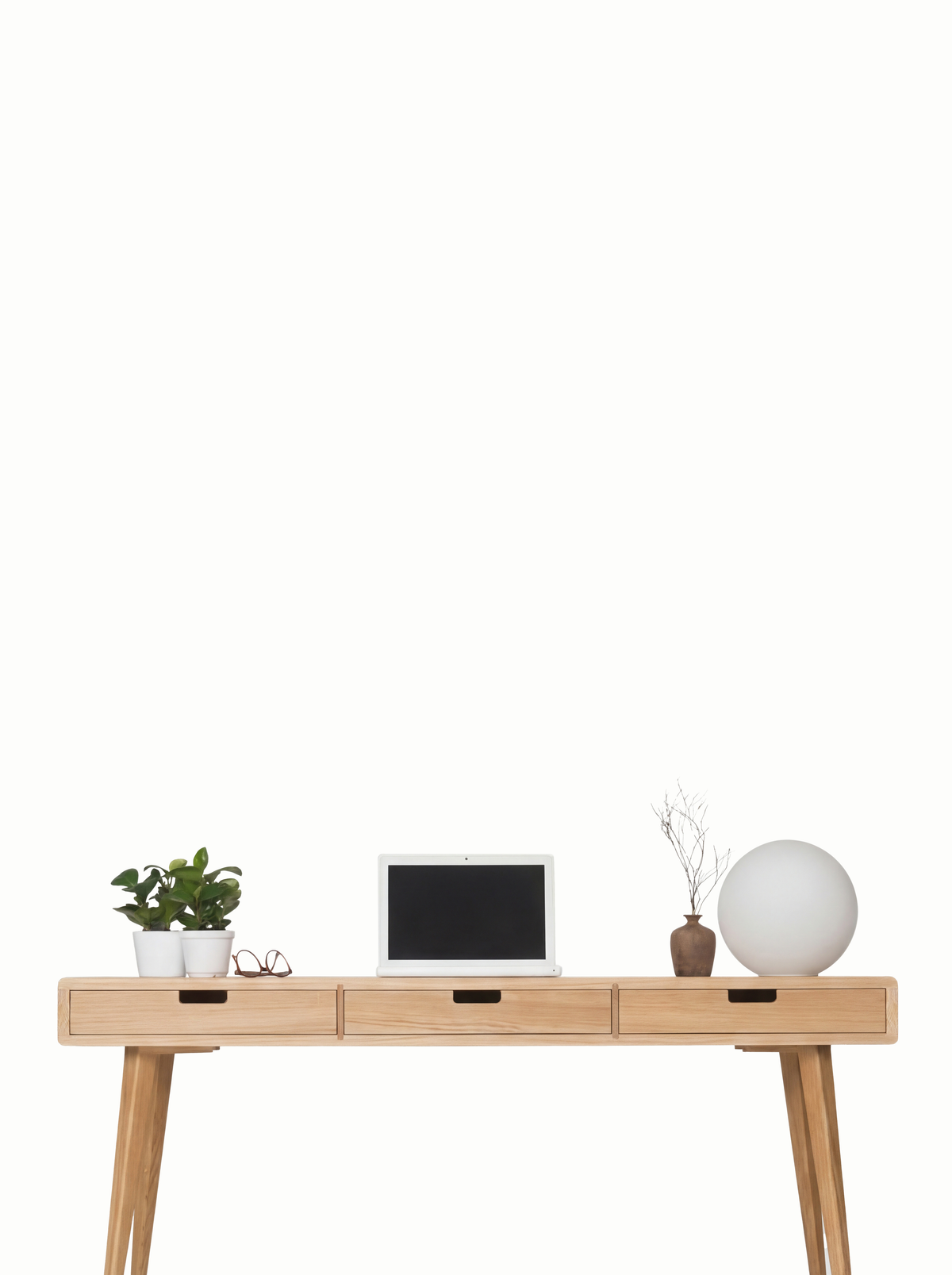 HEIM 140 desk in solid oak, front view against a white wall with three oak drawer fronts, a laptop and a globe lamp