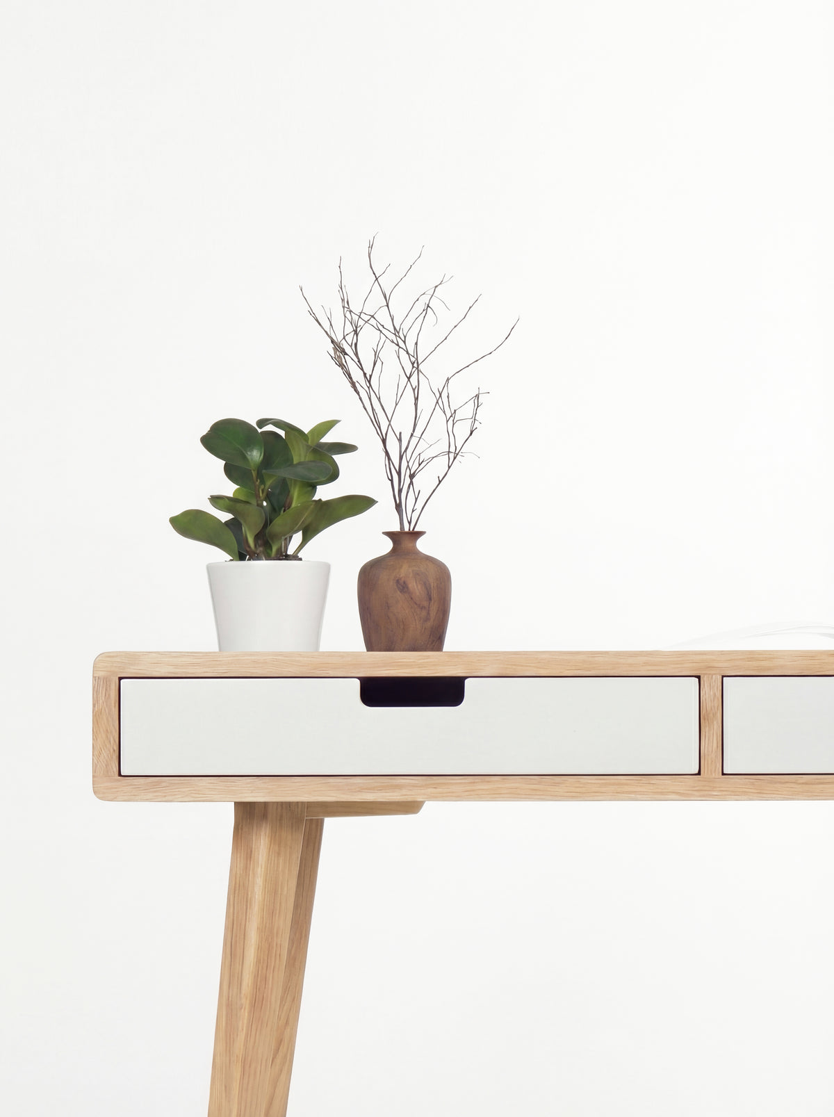 HEIM 140 desk in solid oak, close-up of a white drawer front with a cut-out grip and an oak leg below