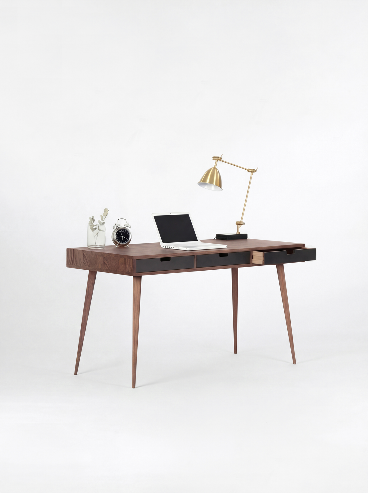 HEIM 140 desk in solid walnut with three black drawer fronts, the right drawer pulled out and a laptop on top