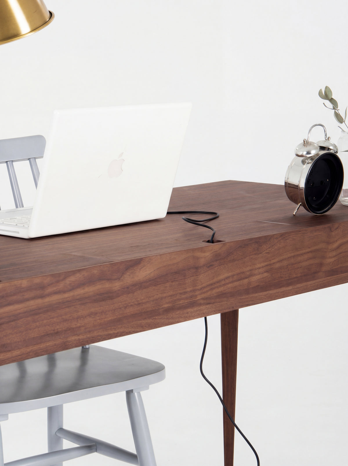 Closed cable flap on the HEIM 140 desk in solid walnut, with a laptop cable running through its notch