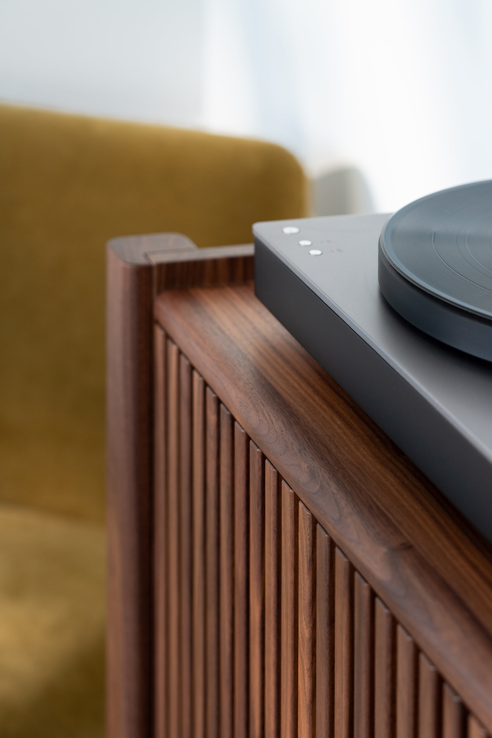 Modern turntable on a wooden cabinet with a muted, minimalist aesthetic.