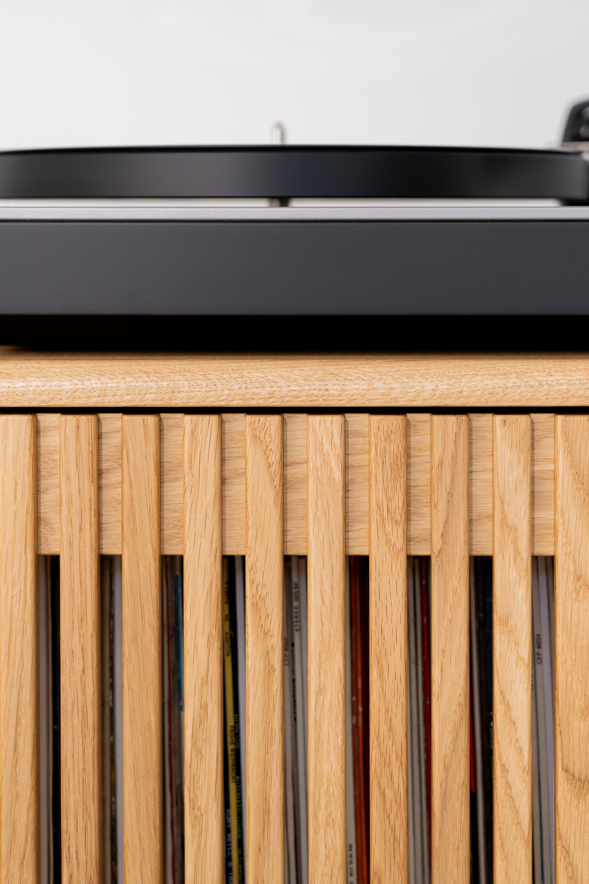 Close-up of a vinyl record player on a wooden cabinet with vertical slats.