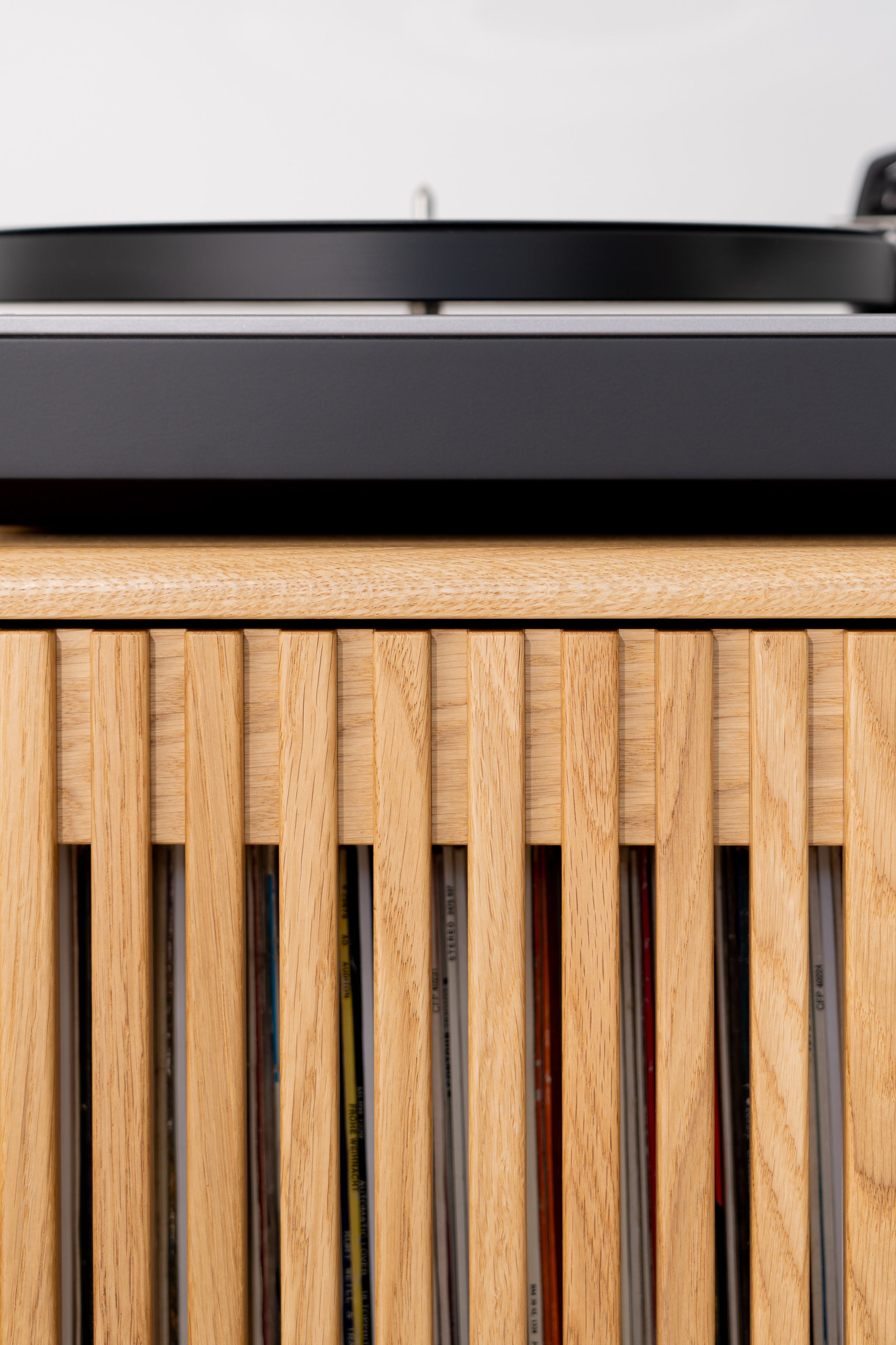 Close-up of a vinyl record player on a wooden cabinet with vertical slats.