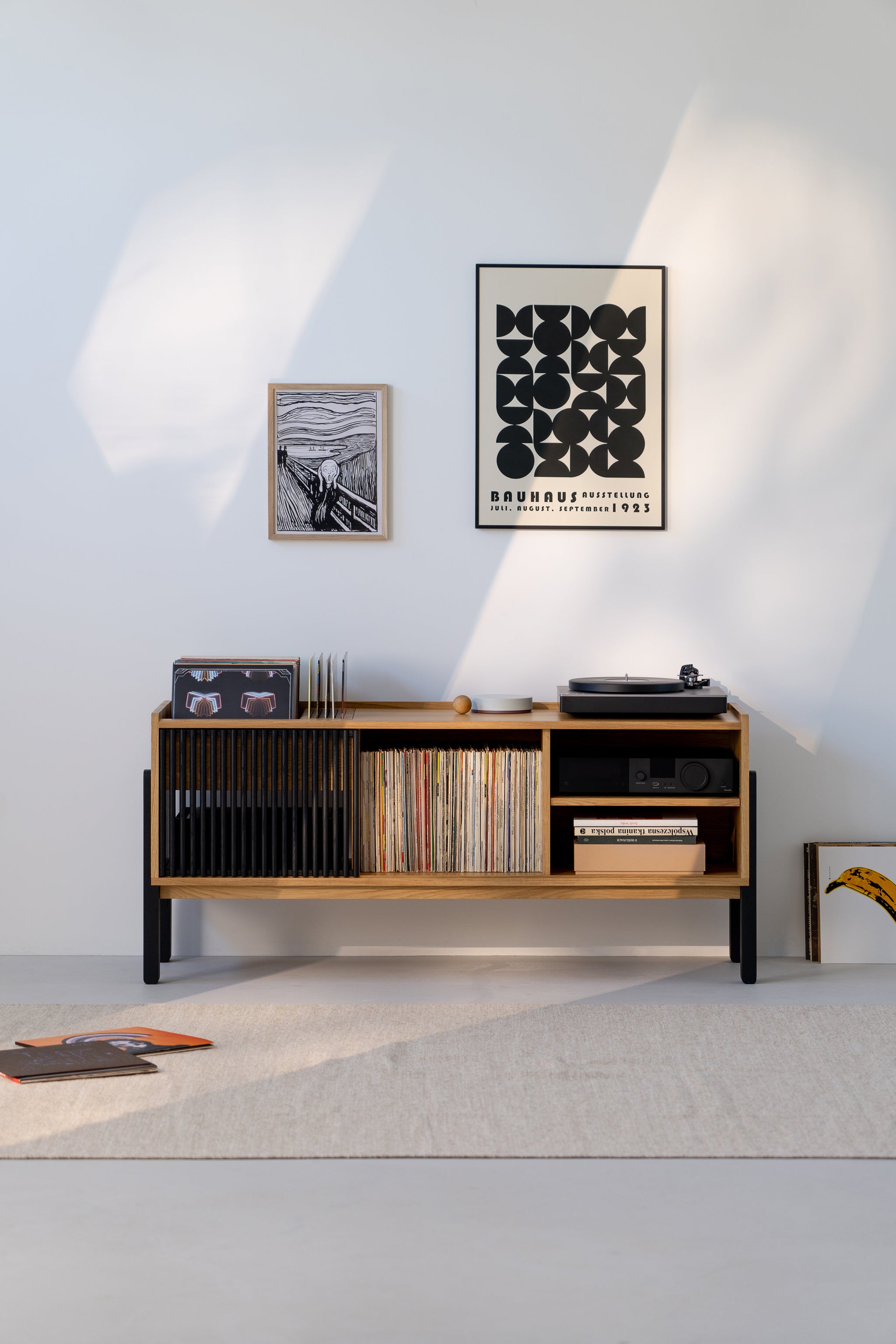 Minimalist room with a wooden record shelf, vinyls, record player, and wall art.