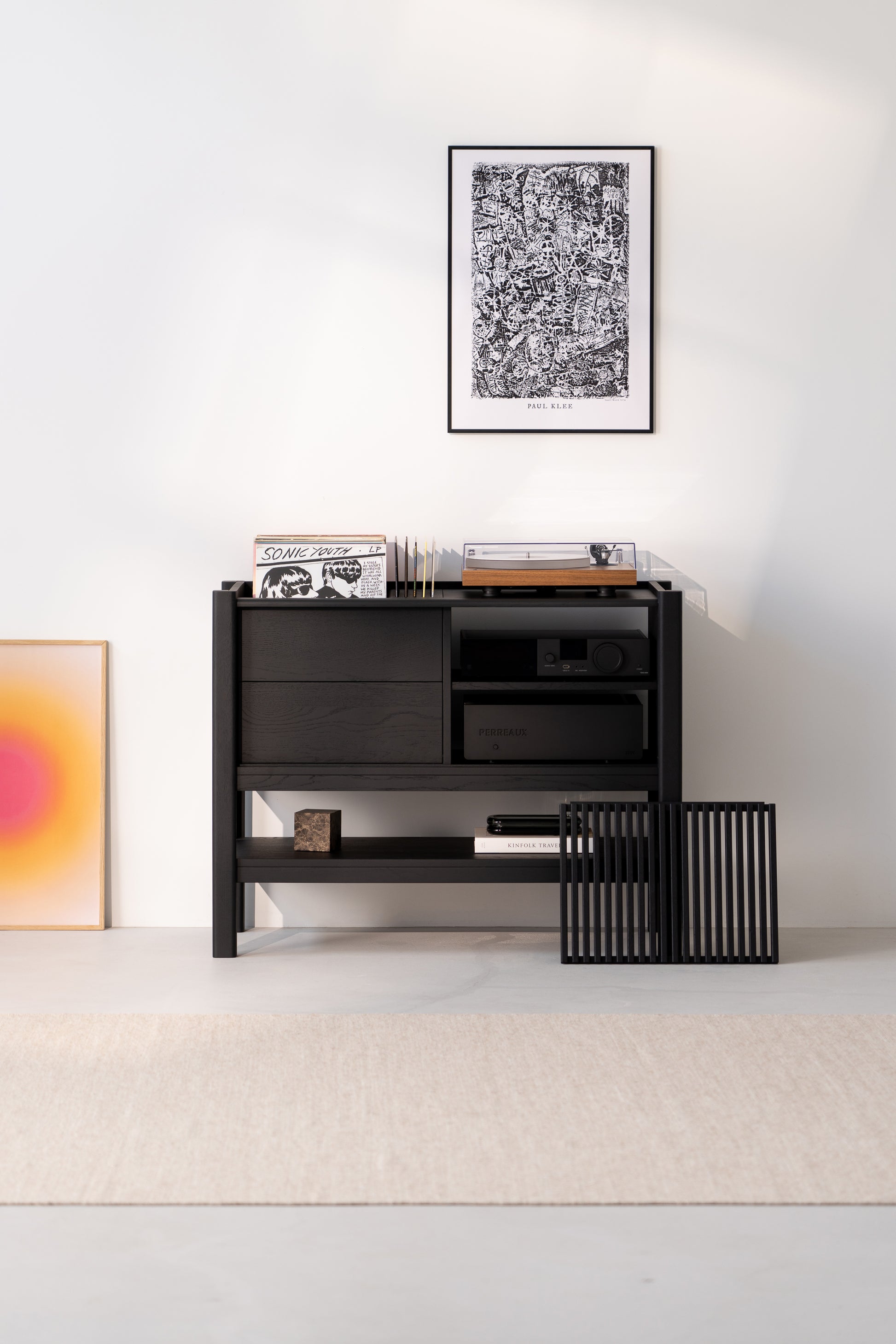 Minimalist room with a black shelf, vinyl records, turntable, and art on the wall.