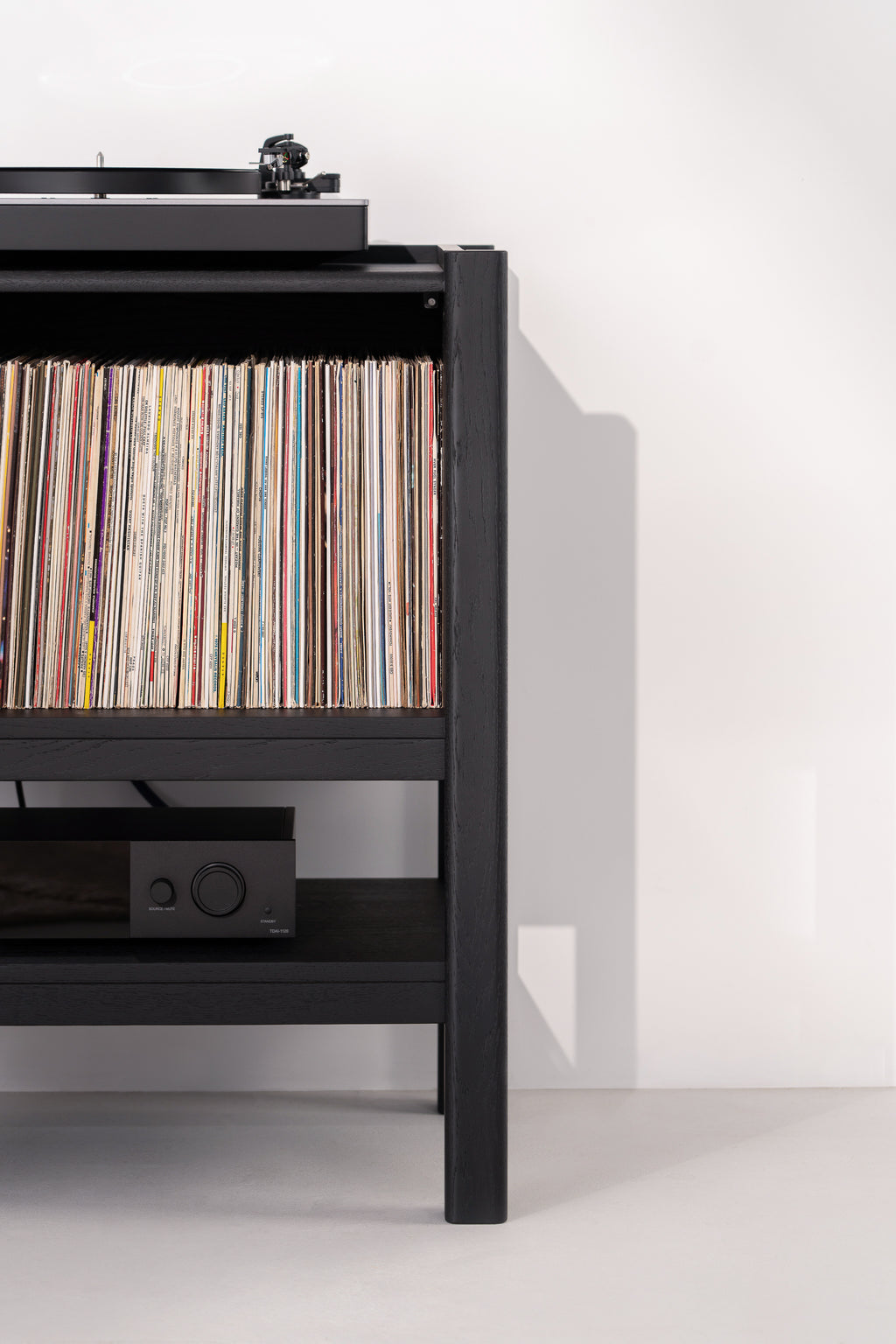 Turntable and vinyl records on a black shelf.
