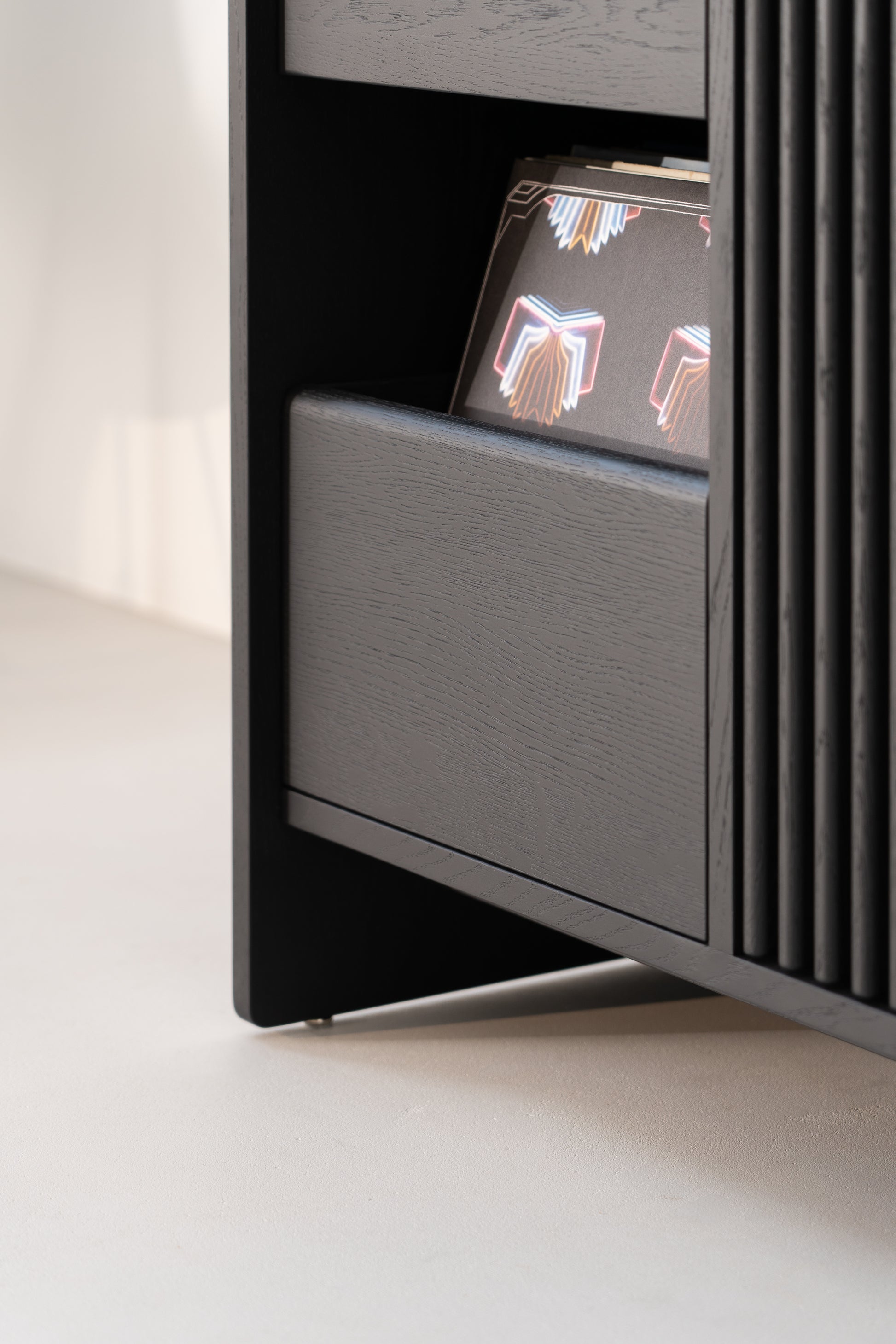 Close-up of a black wooden shelf with a decorative book featuring colorful patterns partially visible.