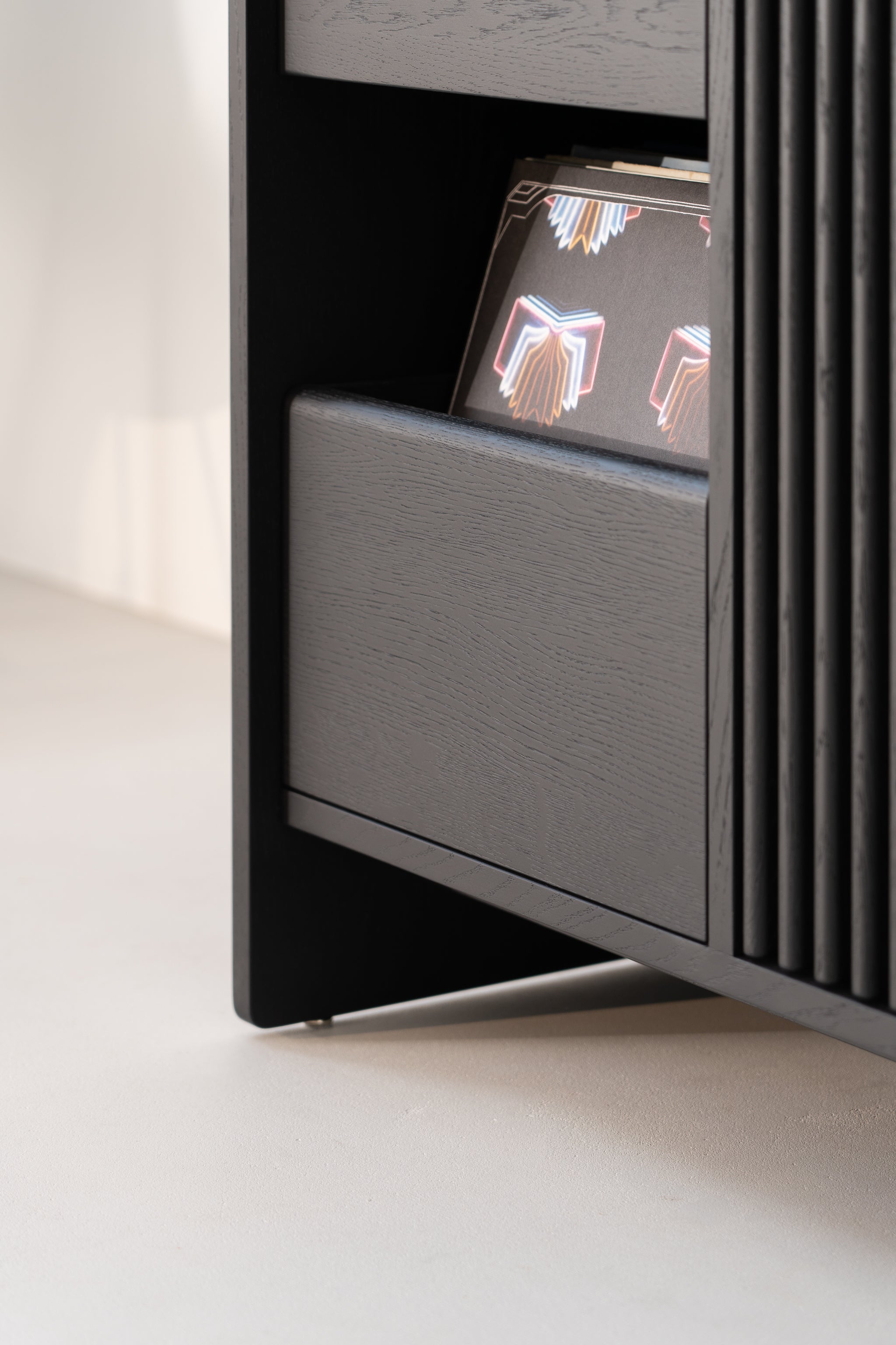 Close-up of a black wooden shelf with a decorative book featuring colorful patterns partially visible.