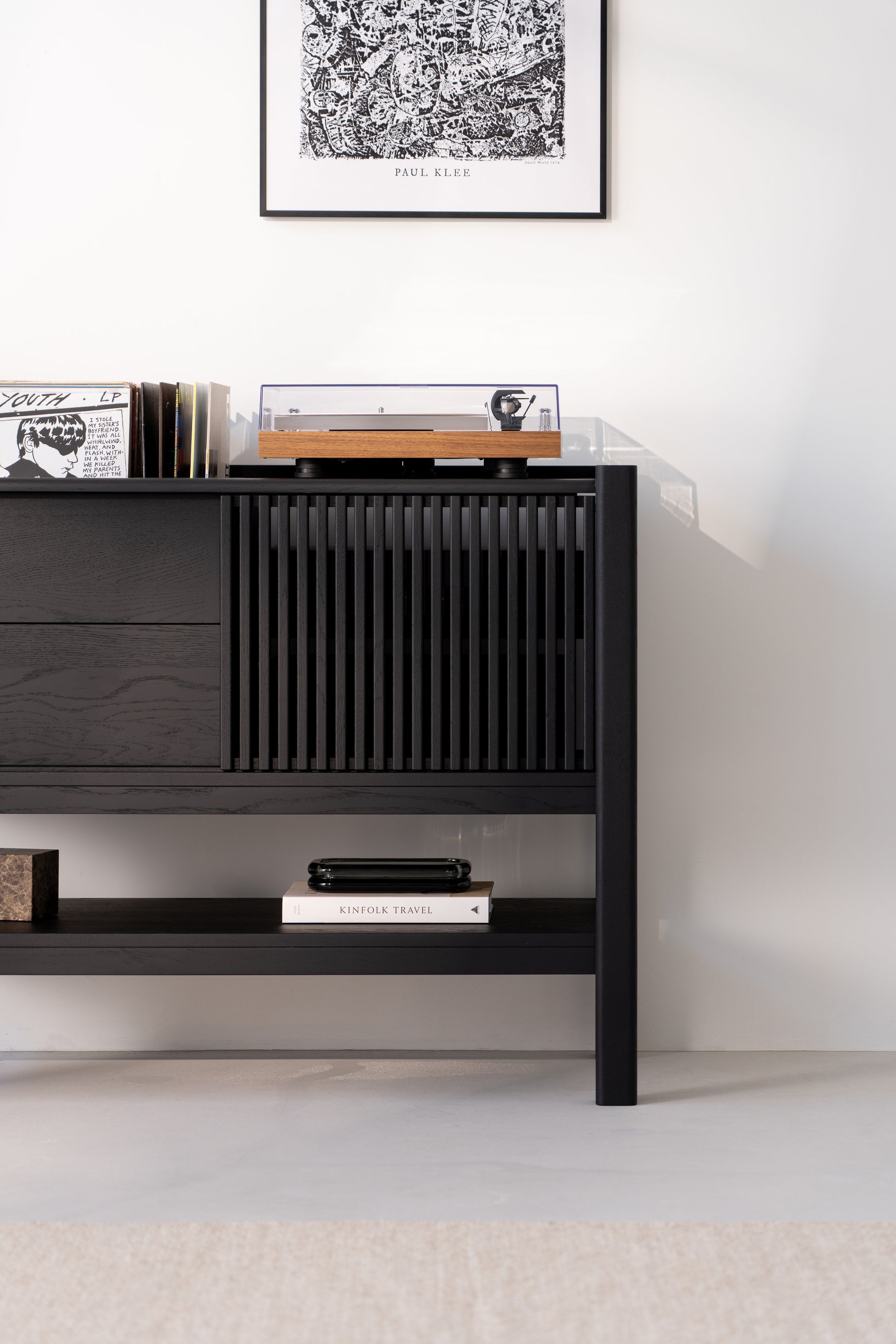 Modern black console with a turntable and books, featuring a Paul Klee artwork above.