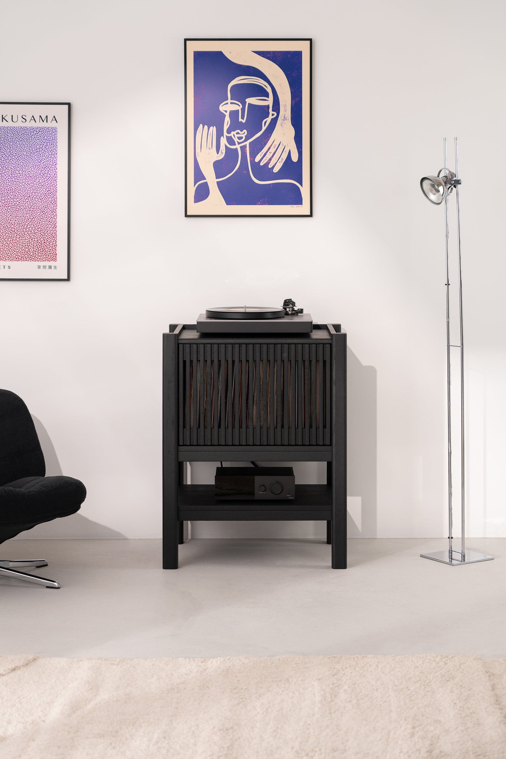 Stylish room with a record player, abstract artwork, and floor lamp. Minimalist decor.