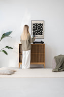 Woman holding a vinyl record at TONN 101 HIGH solid oak cabinet with one sliding front open, turntable on top