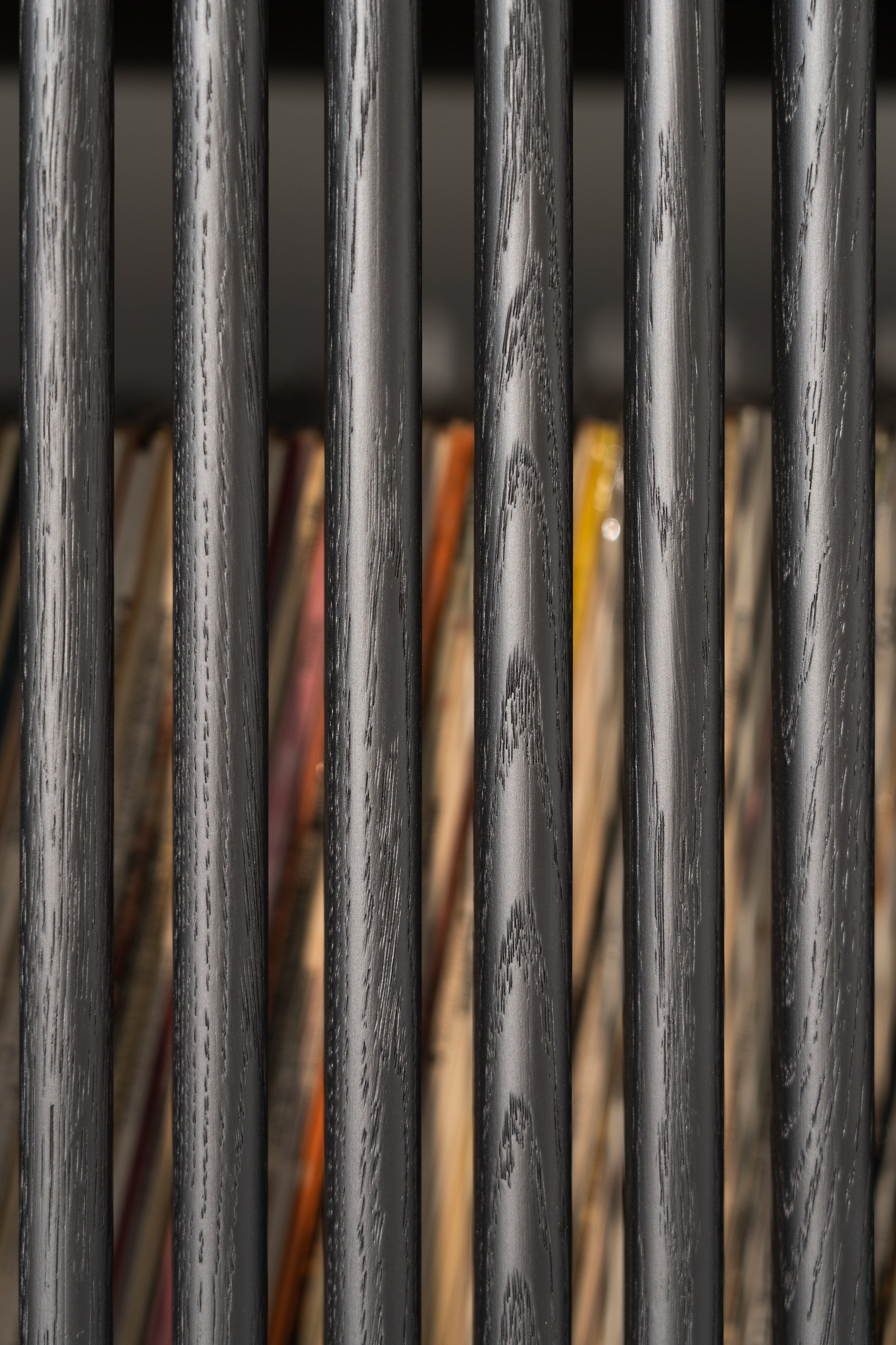 Close-up of black wooden bars with colorful items in the background.