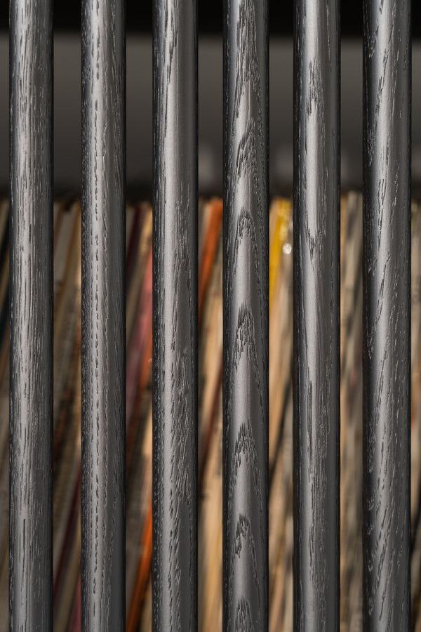 Close-up of black wooden bars with colorful items in the background.
