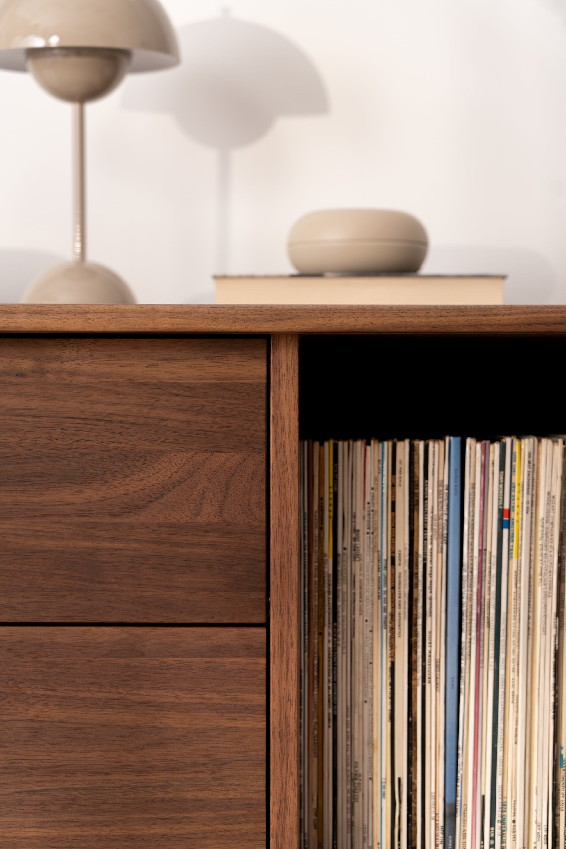 Wooden cabinet with a lamp, book, and container on top, and a stack of magazines inside.