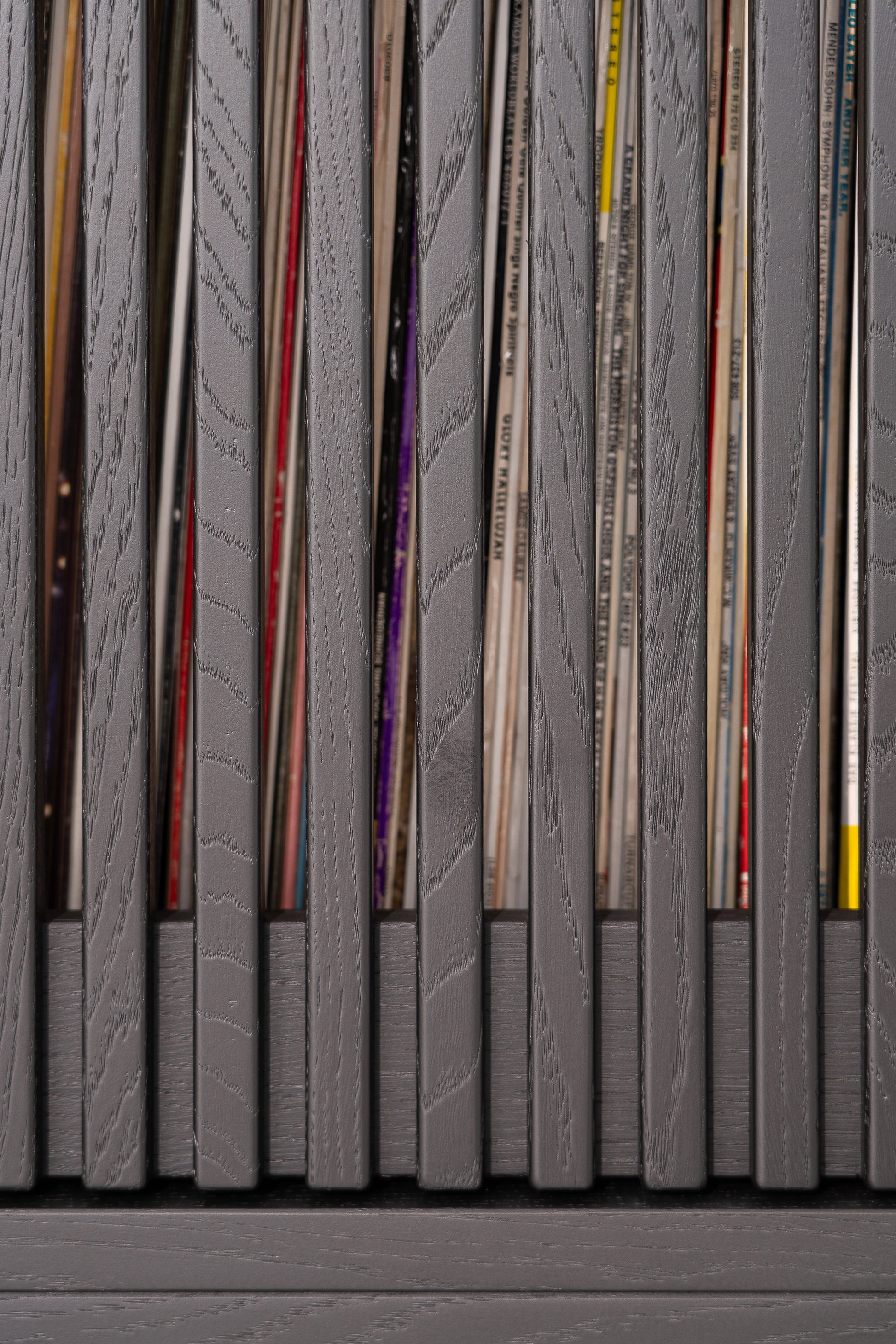 Gray wooden slats with vinyl records peeking through gaps.