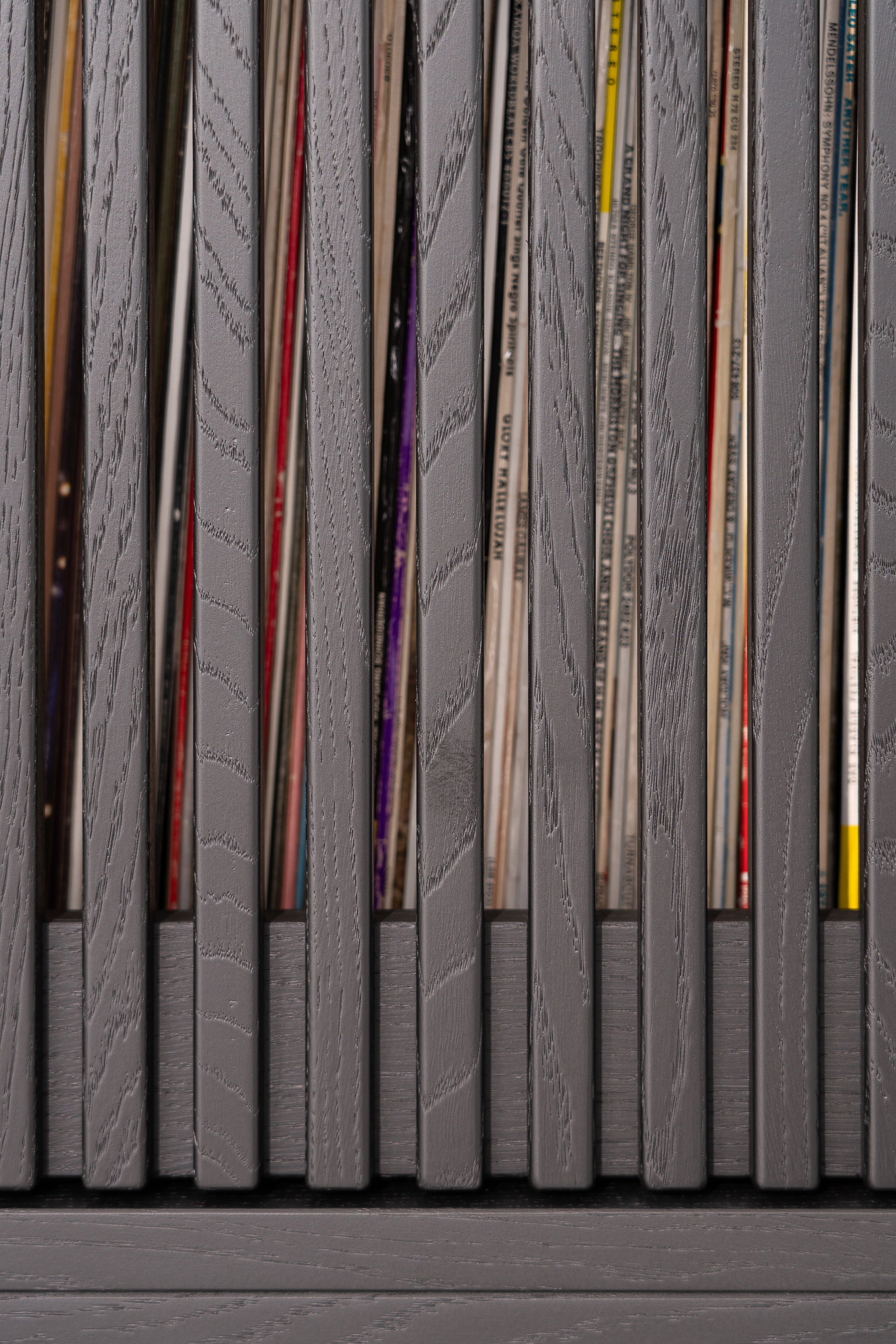Gray wooden slats with vinyl records peeking through gaps.