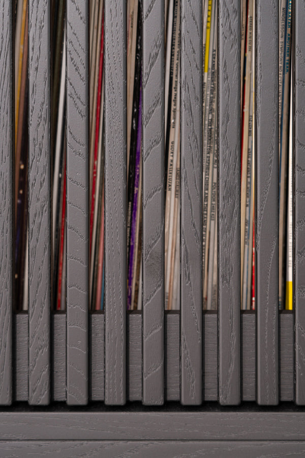 Gray wooden slats with vinyl records peeking through gaps.