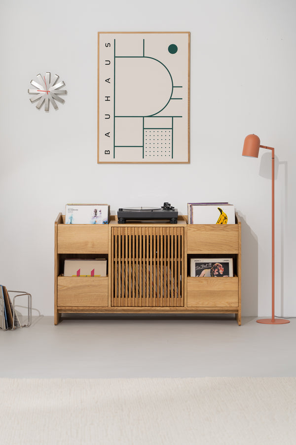 Front view of the FUSE X in solid oak with its slatted door, side niches, two drawers and a turntable on top