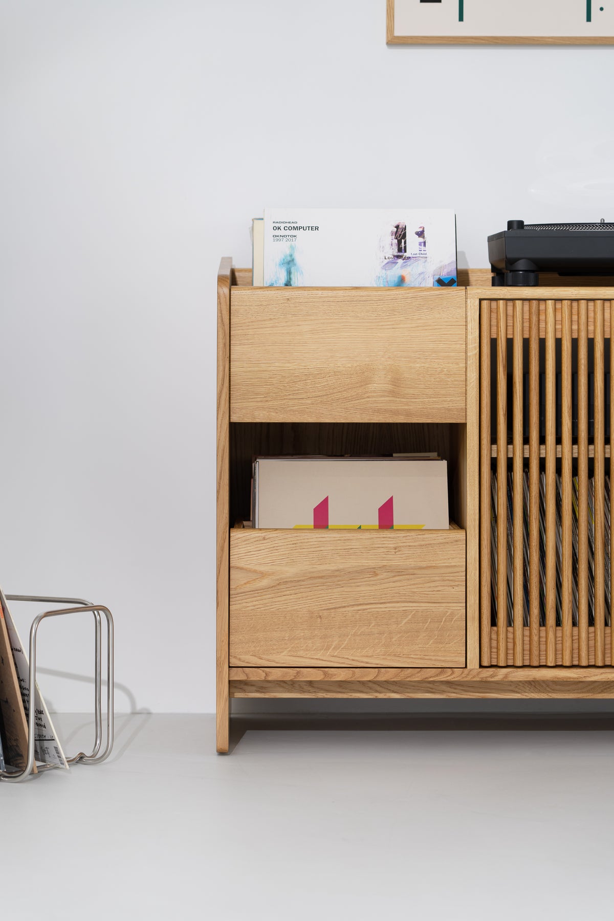 Left half of the FUSE X in solid oak, front view of the top record niche, closed drawer and part of the slatted door