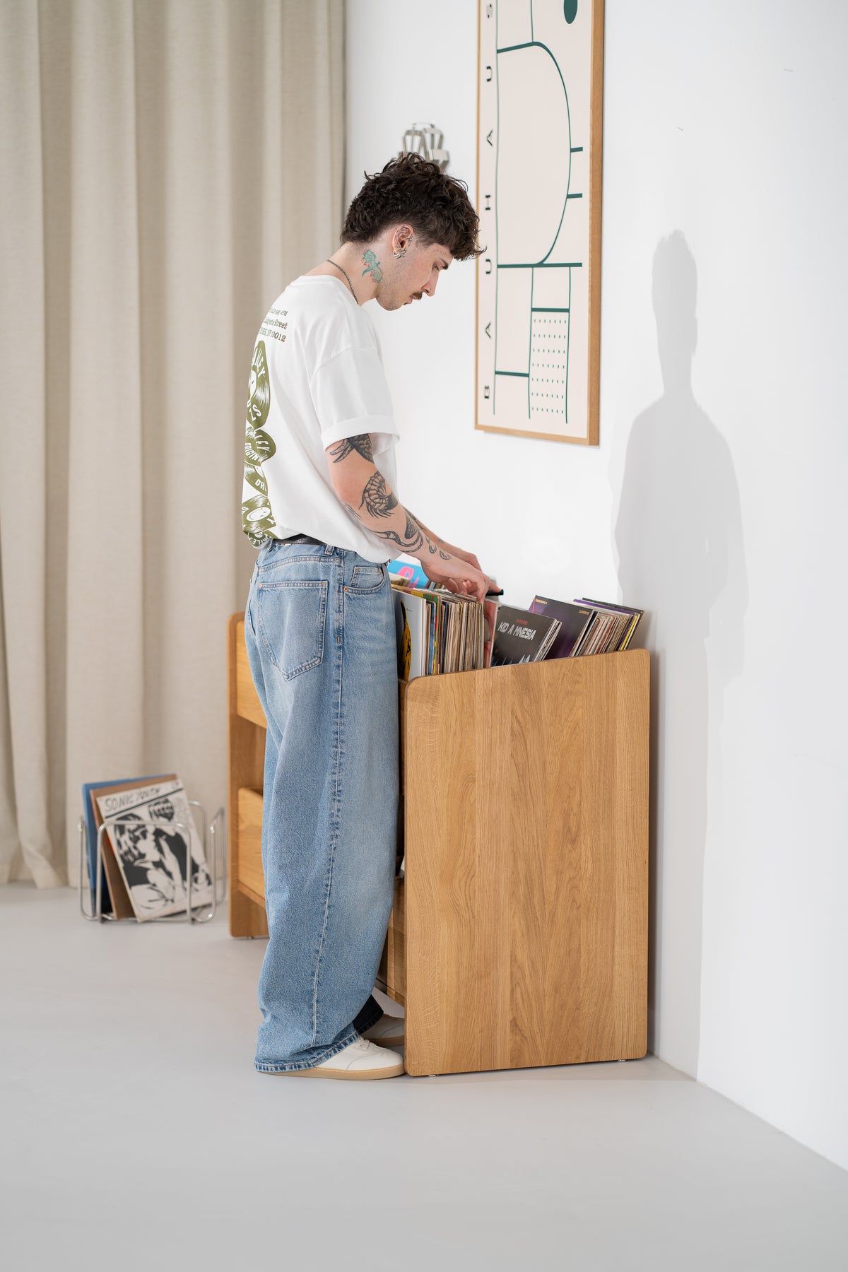 Side view of the FUSE X in solid oak against a wall as a man browses records in the top niche