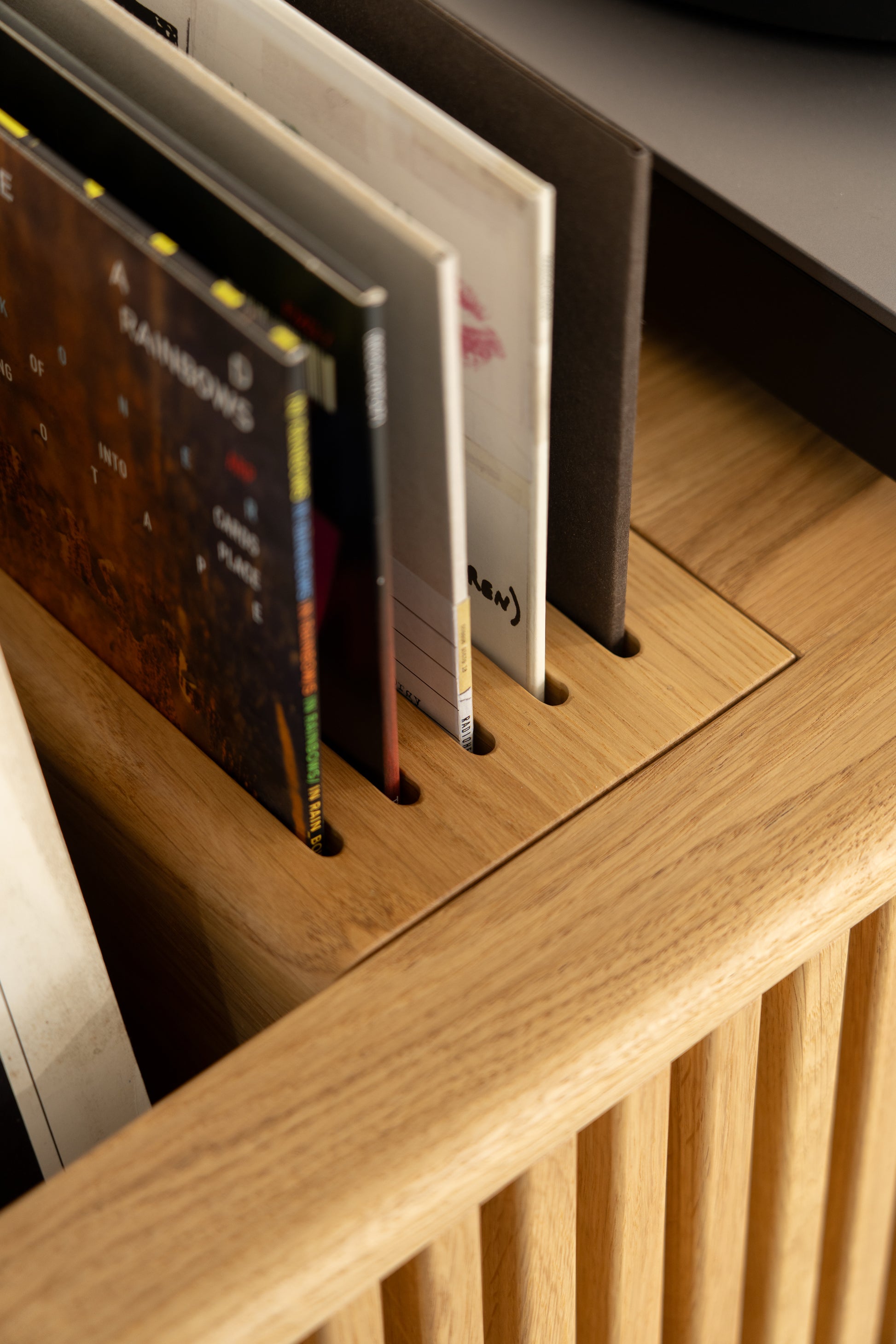 Vinyl records neatly placed in a wooden storage rack.