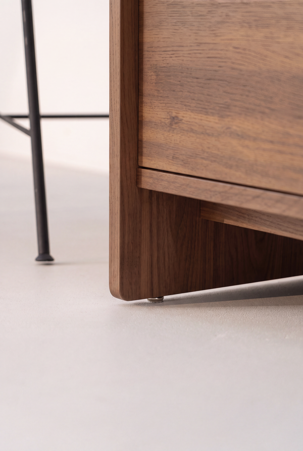FUSE XX in solid walnut, close-up of the lower side panel with a small metal foot and the drawer front above