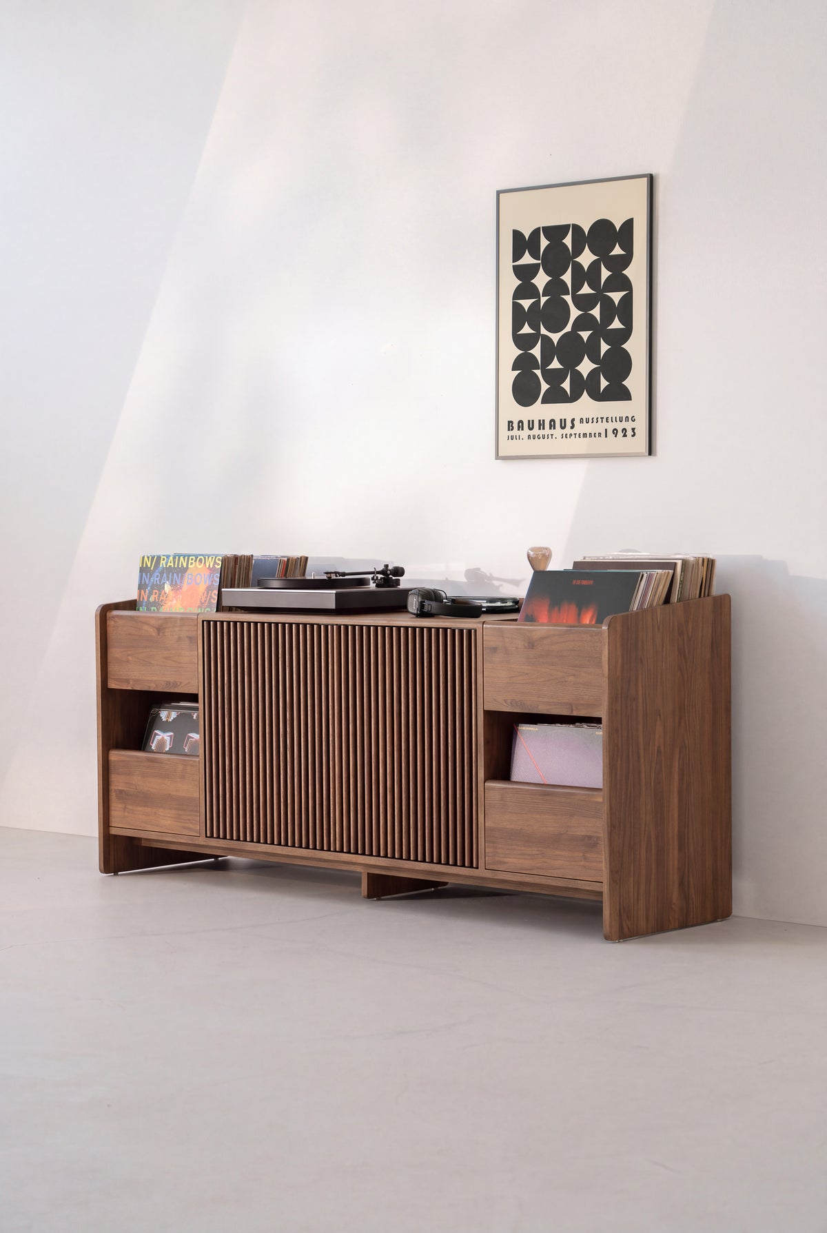 FUSE XX console in solid walnut at an angle in a sunlit room, doors closed and records in the niches and on top