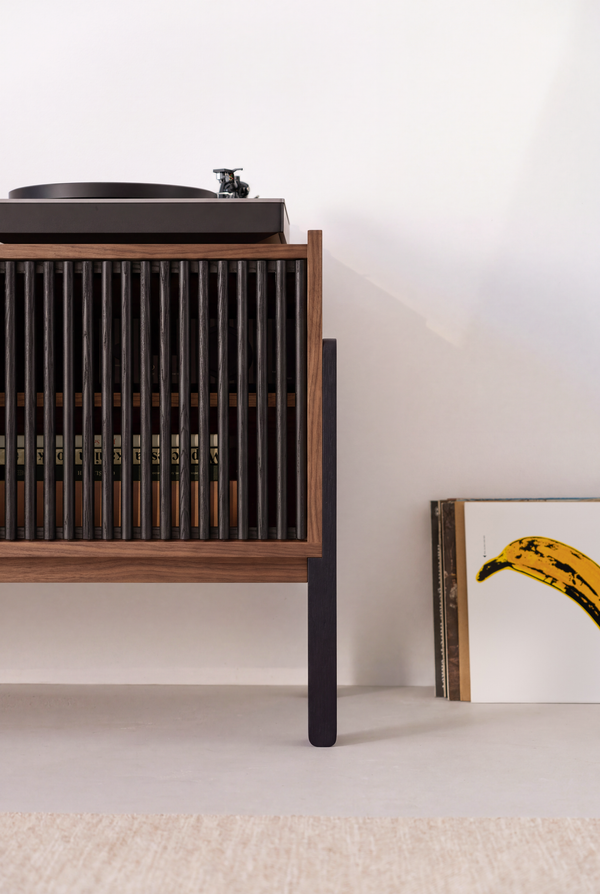 One end of VIBE in solid walnut, with records visible through the closed black slatted front and a turntable above