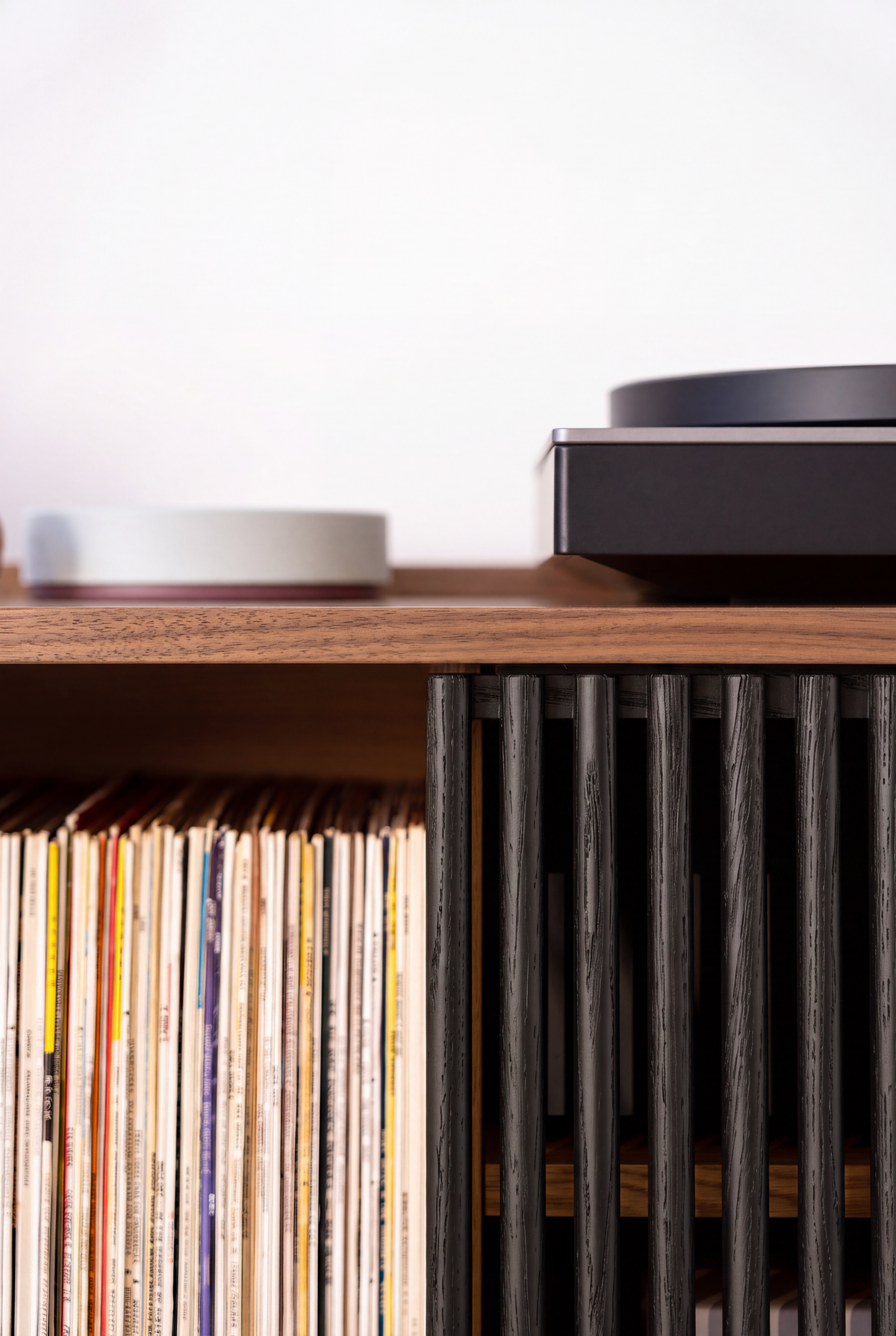 Close-up of VIBE in solid walnut, with black slats beside upright records under the top and a turntable above