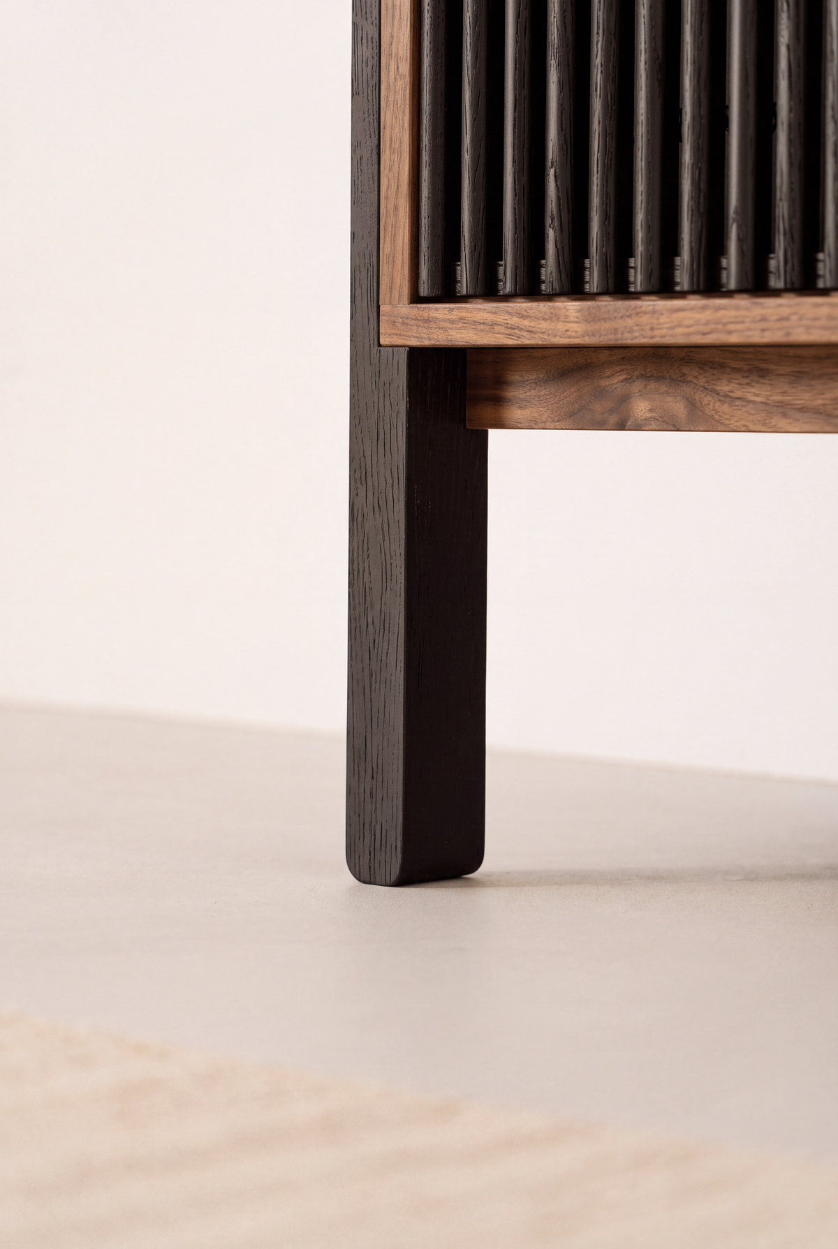 Low close-up of VIBE in solid walnut, with a square black leg joined to the walnut bottom frame beneath black slats