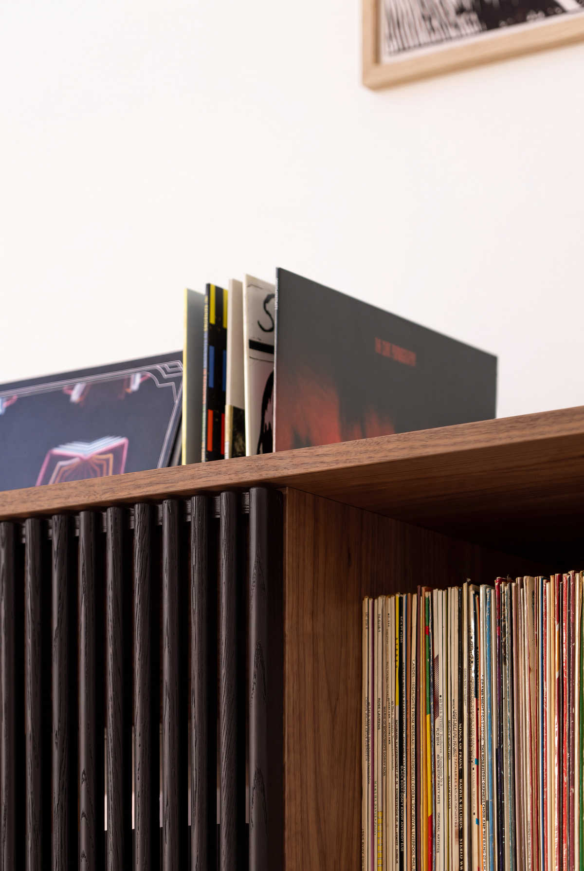 VIBE in solid walnut, close-up from below with records leaning in the top niche and a row of records beneath