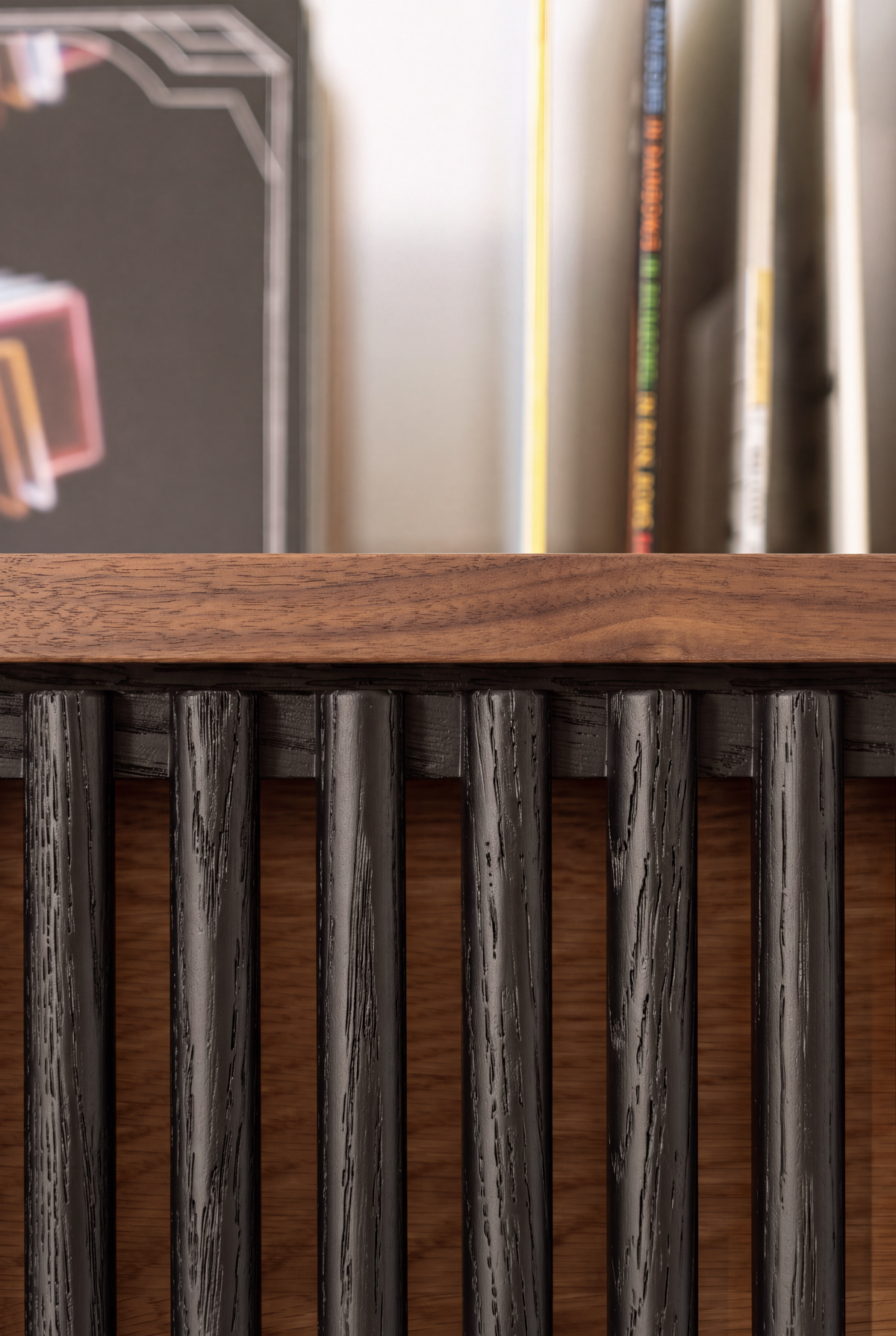 Macro of VIBE in solid walnut, showing open grain on rounded black slats beneath the top edge, with records behind