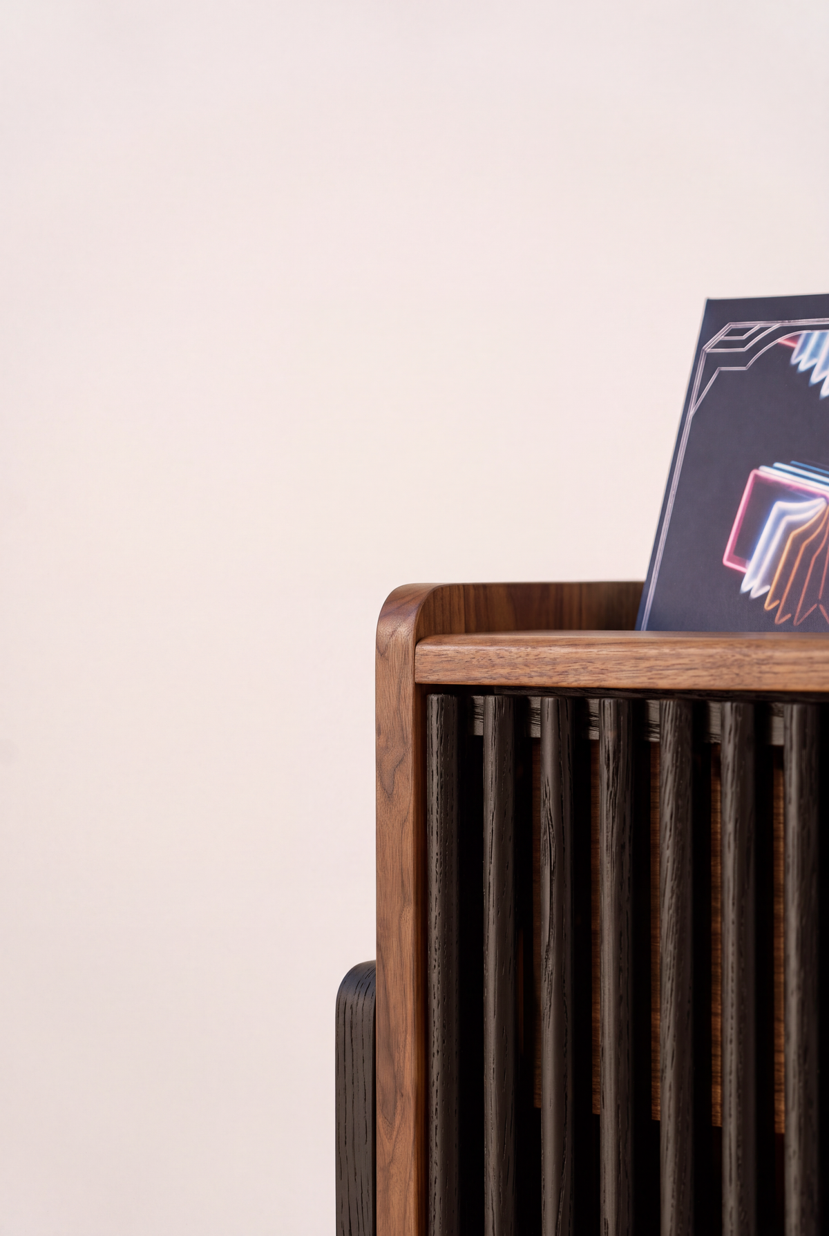 VIBE in solid walnut, close-up of the rounded top corner with a record leaning in the niche and black slats below