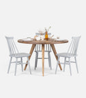 OKKO round kitchen table in reclaimed solid oak with three gray spindle-back chairs, set with plates and an amber bottle