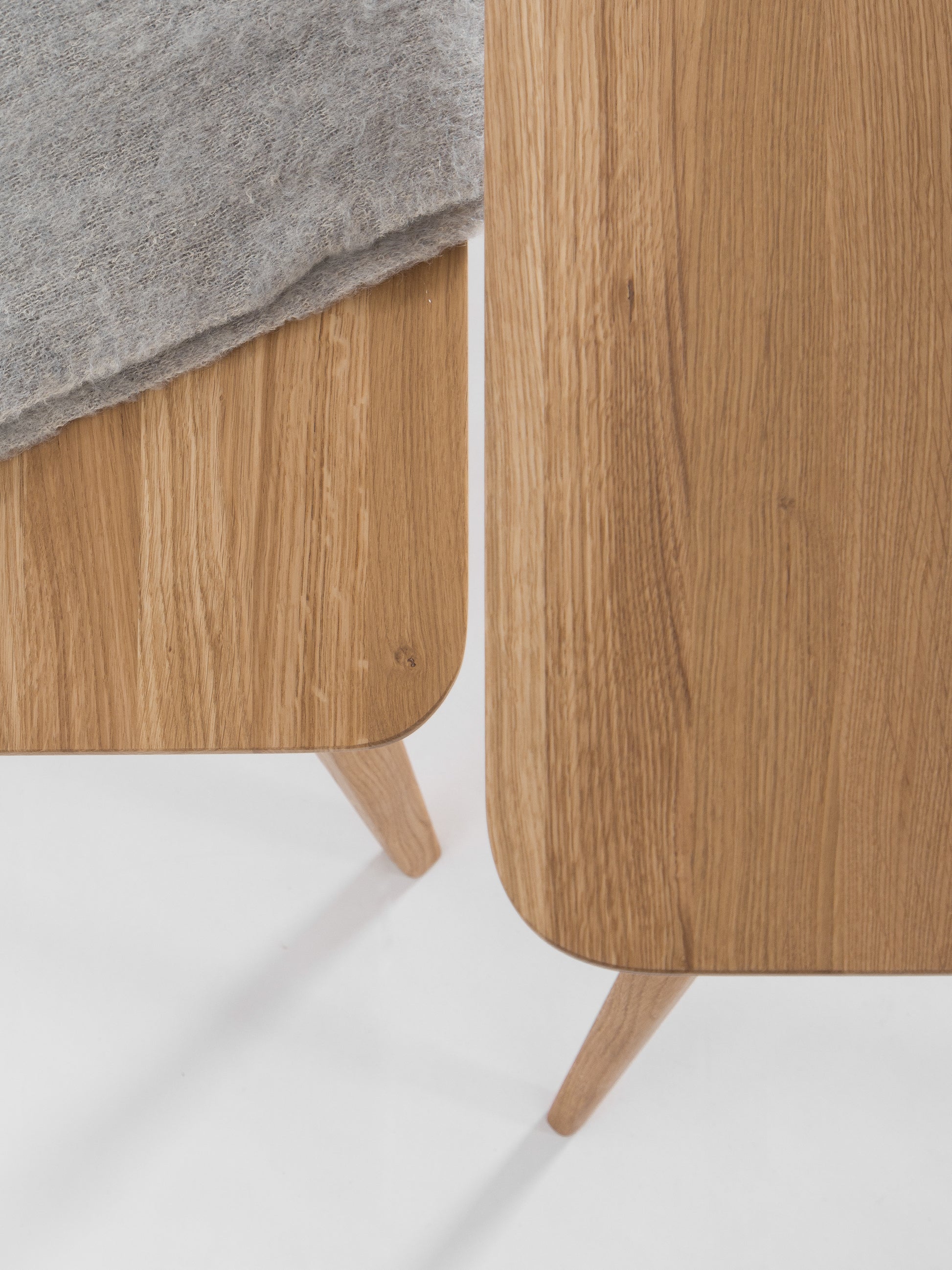Close-up of two wooden tables with rounded edges, one covered partially by a gray fabric.