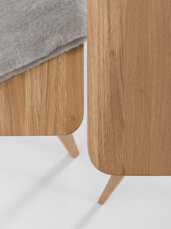 Close-up of two wooden tables with rounded edges, one covered partially by a gray fabric.