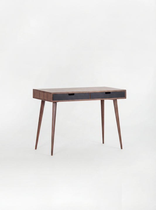 Empty HEIM 105 desk in solid walnut with two black drawer fronts, angled against a plain white background