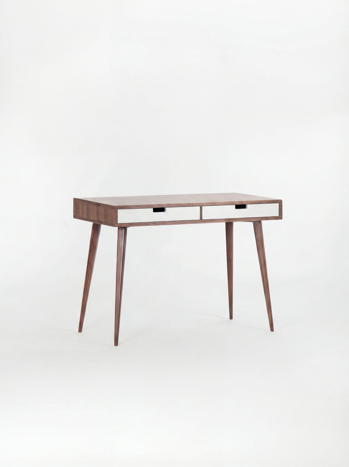 HEIM 105 desk in solid walnut, shown empty at an angle with two white drawer fronts on a white background