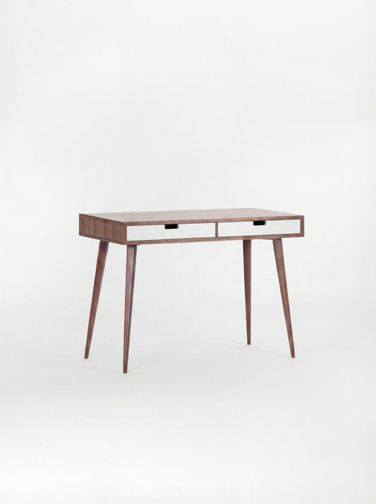 HEIM 105 desk in solid walnut, shown empty at an angle with two white drawer fronts on a white background