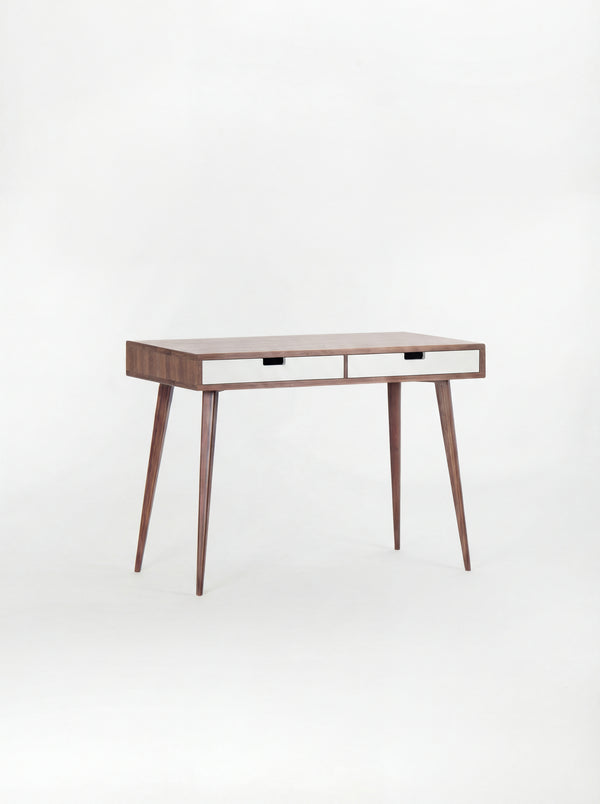 HEIM 105 desk in solid walnut, shown empty at an angle with two white drawer fronts on a white background