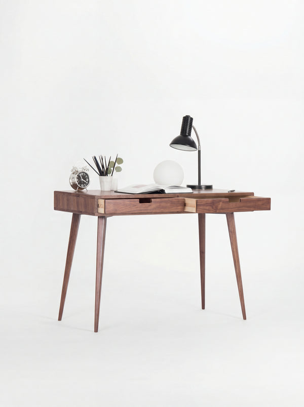 HEIM 105 desk in solid walnut at an angle, both drawers slightly open to show light plywood sides, with lamps on top