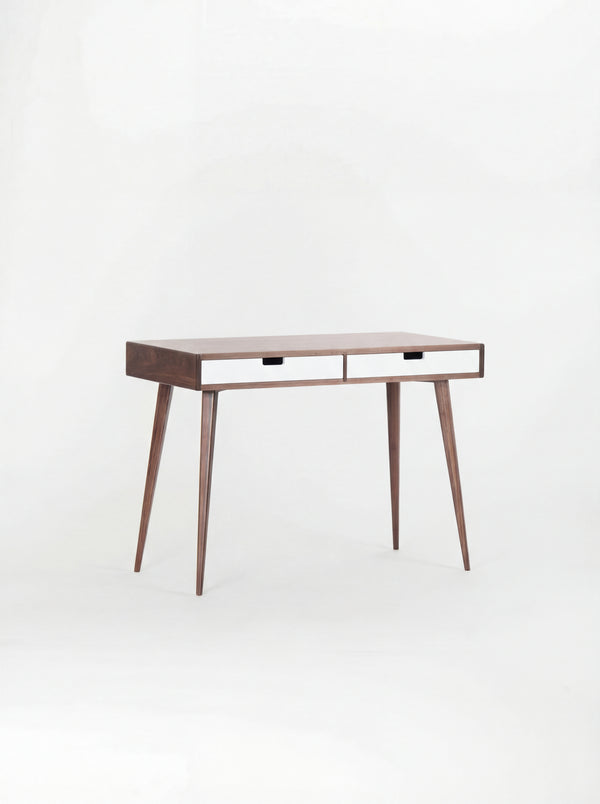 Angled HEIM 105 desk in walnut wood with two white drawer fronts, against a plain white background