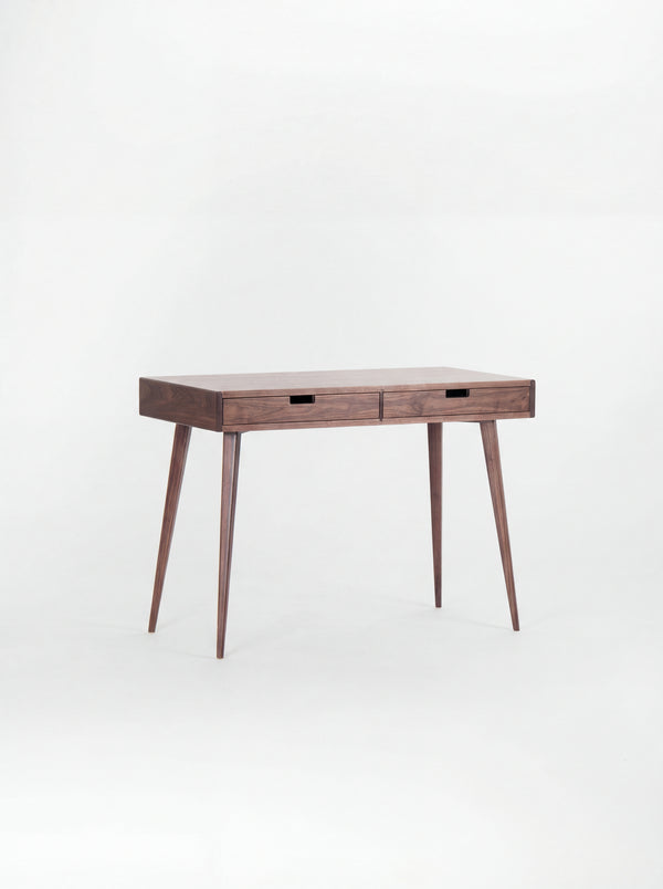 HEIM 105 desk in walnut wood with a bare top and two wooden drawer fronts, shown at an angle