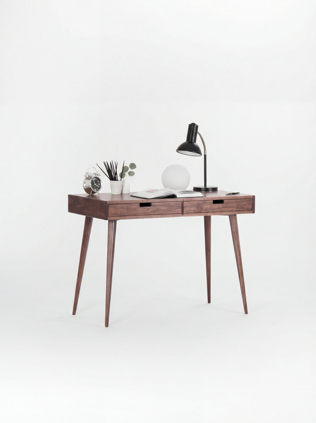 HEIM 105 small desk with drawers in walnut wood, angled view with two lamps and an open book