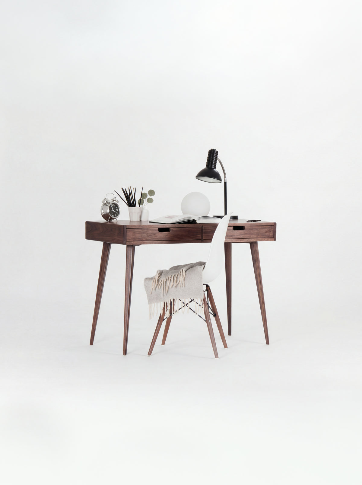 HEIM 105 desk in walnut wood with a white shell chair draped with a fringed blanket