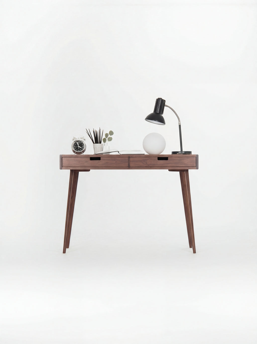 HEIM 105 desk in walnut wood, front view with wooden drawer fronts, lamps and an alarm clock