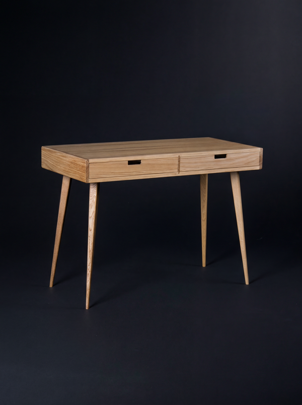 Empty HEIM 105 desk in oak wood on a dark background, angled to show wooden drawer fronts and splayed legs