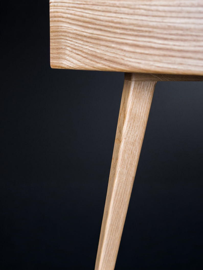 Leg joint beneath the corner of the HEIM 105 desk in oak wood, with the side panel's end grain visible