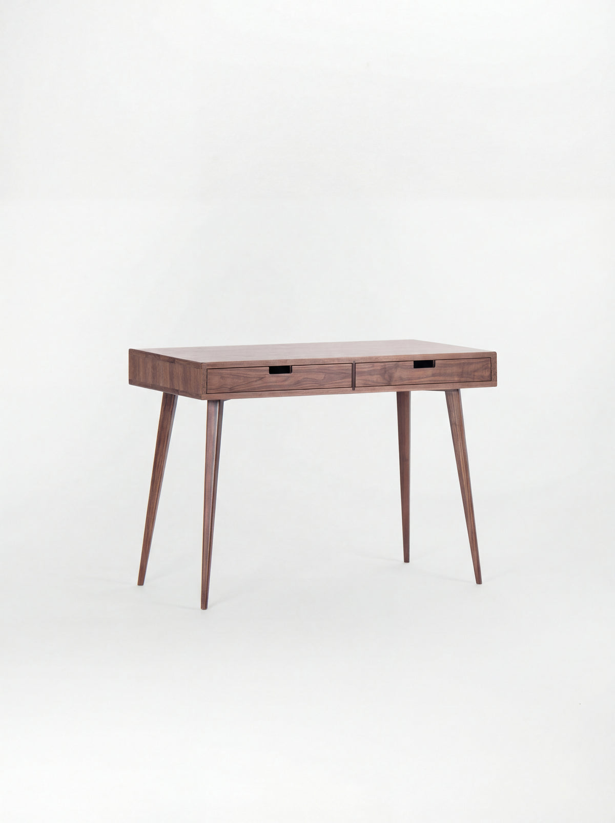 Empty HEIM 105 small wooden desk in solid walnut, angled view with two wooden drawer fronts